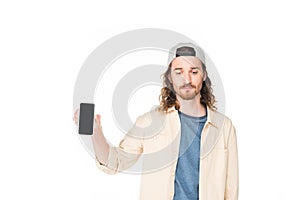 Sad young man holding smartphone in hands and looking down