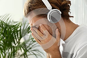 Sad young man listening to music at home