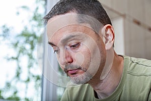 Sad young man looking down. Interior image.