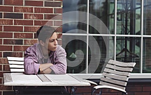 Sad young man sitting at a table near a wall