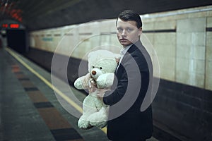 Sad young man with a teddy bear.