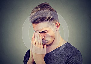 Sad young man with tensed face expression praying