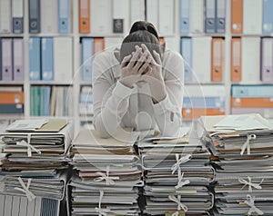 Sad young office worker overloaded with work