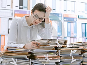 Sad young office worker overloaded with work