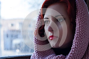 Sad young red-haired girl, a sad girl look with a scarf on her head. Sad dramatic portrait of a woman