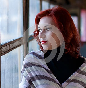 Sad young red-haired girl, a sad girl look with a scarf on her head. Sad dramatic portrait of a woman
