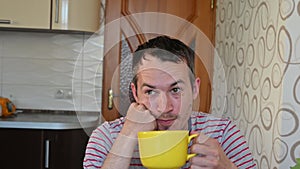 Sad young unshaven man sitting in the kitchen. Home quarantine