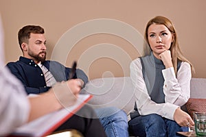 Sad young wife and her husband during meeting with marriage counselor