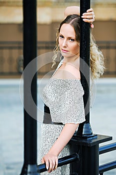 Sad young woman against a railing.