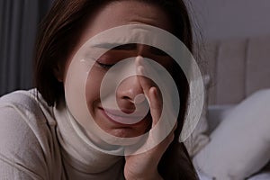 Sad young woman crying on bed at home, closeup. Loneliness concept
