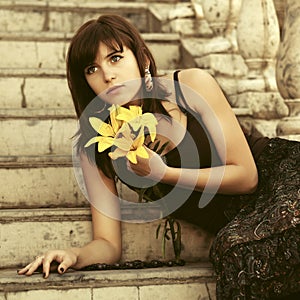 Sad young woman with a flowers sitting on steps