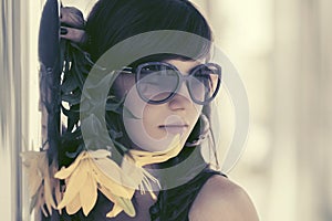 Sad young woman with a flowers standing at the wall