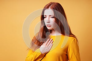 sad young woman with hand on chest feeling heartache or heartburn