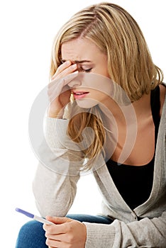 Sad young woman holding pregnancy test