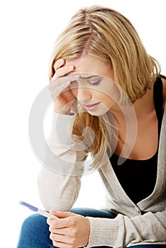 Sad young woman holding pregnancy test