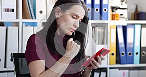 Sad young woman looks at smartphone screen