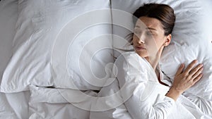 Sad young woman lying in bed feeling lonely