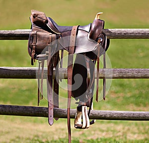 Saddle, horse and farm on ranch fence, riding and equestrian sports in country side. Western, cowboys and field in Texas