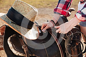 Saddle prepared for horse riding by young woman cowgirl