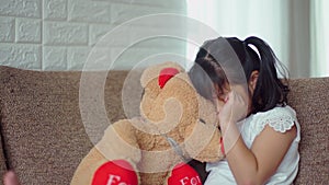 Sadness girl hugging large teddy bear and crying