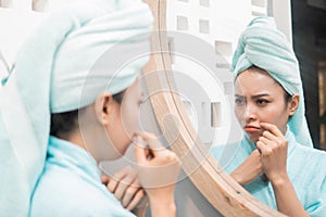 sadness girl with pimple on the cheek when looks to the mirror