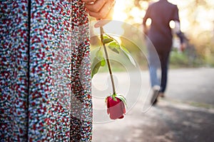 Sadness Love in Ending of Relationship Concept, Broken Heart Woman Standing with a Red Rose on Hand, Blurred Man in Back Side photo