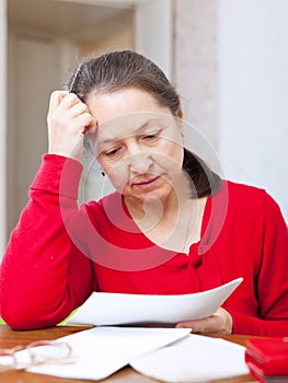 Sadness mature woman with bills