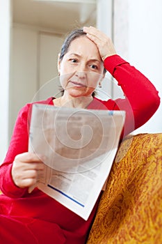 Sadness mature woman reading newspaper