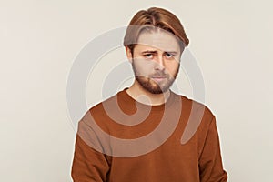 Sadness and resentment emotions. Portrait of unhappy bearded man in sweatshirt. isolated on gray background