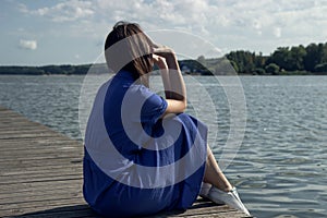 Sadness Woman Sitting by the River on pier. Empty place for text. Bad Day Concept