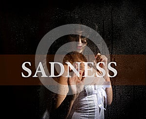 Sadness written on virtual screen. hand of young woman melancholy and sad at the window in the rain.