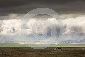 Safari car on a road in Ngorongoro National Park, Tanzania with beautiful clouds in background. Wild nature of Africa