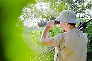 Safari tour: picture of male tourist or exploring scientist in pith helmet having fun observing looking in magnification scope