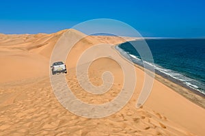 Safari trip by car through sand dunes on ocean shore of Sandwich harbour, extreme travel adventure inNamibia, South Africa