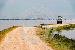 A safari van on a dirt road in the panoramic savannah grassland landscapes of Amboseli National Park in Kenya