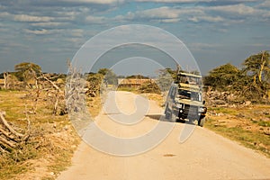 A safari van on a dirt road in the panoramic savannah grassland landscapes of Amboseli National Park in Kenya