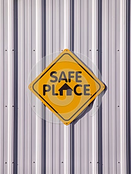 Yellow `Safe place` sign of a light metal wall