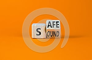 Safe and sound symbol. Turned a wooden cube and changed the word `safe` to `sound` or vice versa. Beautiful orange table, oran