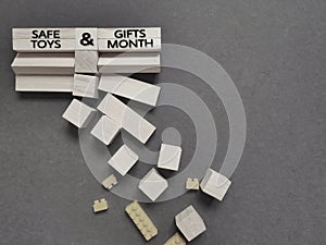 safe toys and gifts month on wooden blocks with heap of toy blocks background