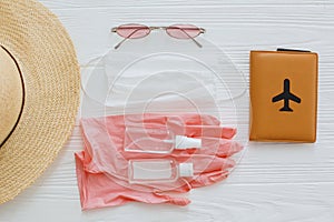 Safe travel in summer 2020 flat lay. Face mask, pink gloves, antiseptic and disinfectant, passport, sunglasses,straw hat on white