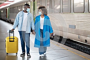 Safe Trip. Black Spouses In Protective Medical Masks Walking At Railway Station