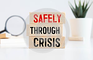 SAFELY THROUGH CRISIS text on wooden block