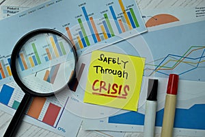 Safely Through Crisis write on sticky notes isolated on office desk