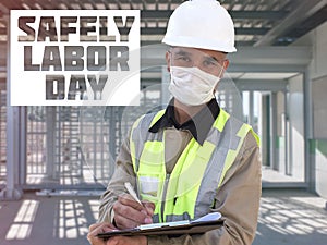 Safely Labor Day. Construction worker in white hardhat and protective mask stands with clipboard opposite checkpoint with