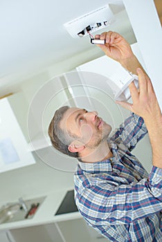 Safety conscious man fitting fire smoke alarm