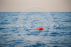 Safety equipment, life buoy or rescue buoy ring with a rope floating in blue sea to rescue people. Yachting, marine background
