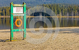 Safety equipment, lifebuoy or rescue buoy hanging on the board. Red lifebuoy on a wooden surface by the lake