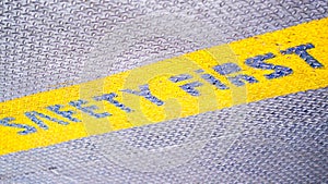 Safety first yellow label floor sign symbol on grey metal texture