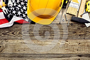 Safety helmet, American flag with construction tools on wooden background. Happy Labor day banner template