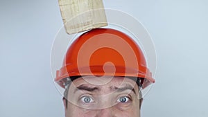 Safety helmet. Brick and a board fall on builder head. Saving a life due to wearing a protective construction helmet. Protection o